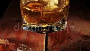 豪华威士忌。 人慢慢地在玻璃杯里搅动金黄色的威士忌，咖啡色的木桌上放着冰块. 不倒翁威士忌。 波旁酒。